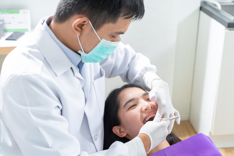 Dentist examining patient teeth and braces during clinical consultation in Ang Mo Kio